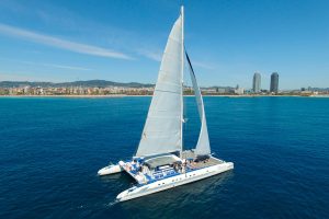 Catamarán Orsom en Barcelona con vista a las Torres Gemelas frente al mar Mediterráneo