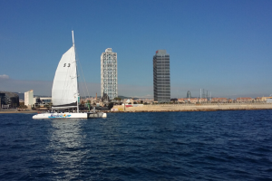 Catamarán navegando con las torres de Barcelona al fondo